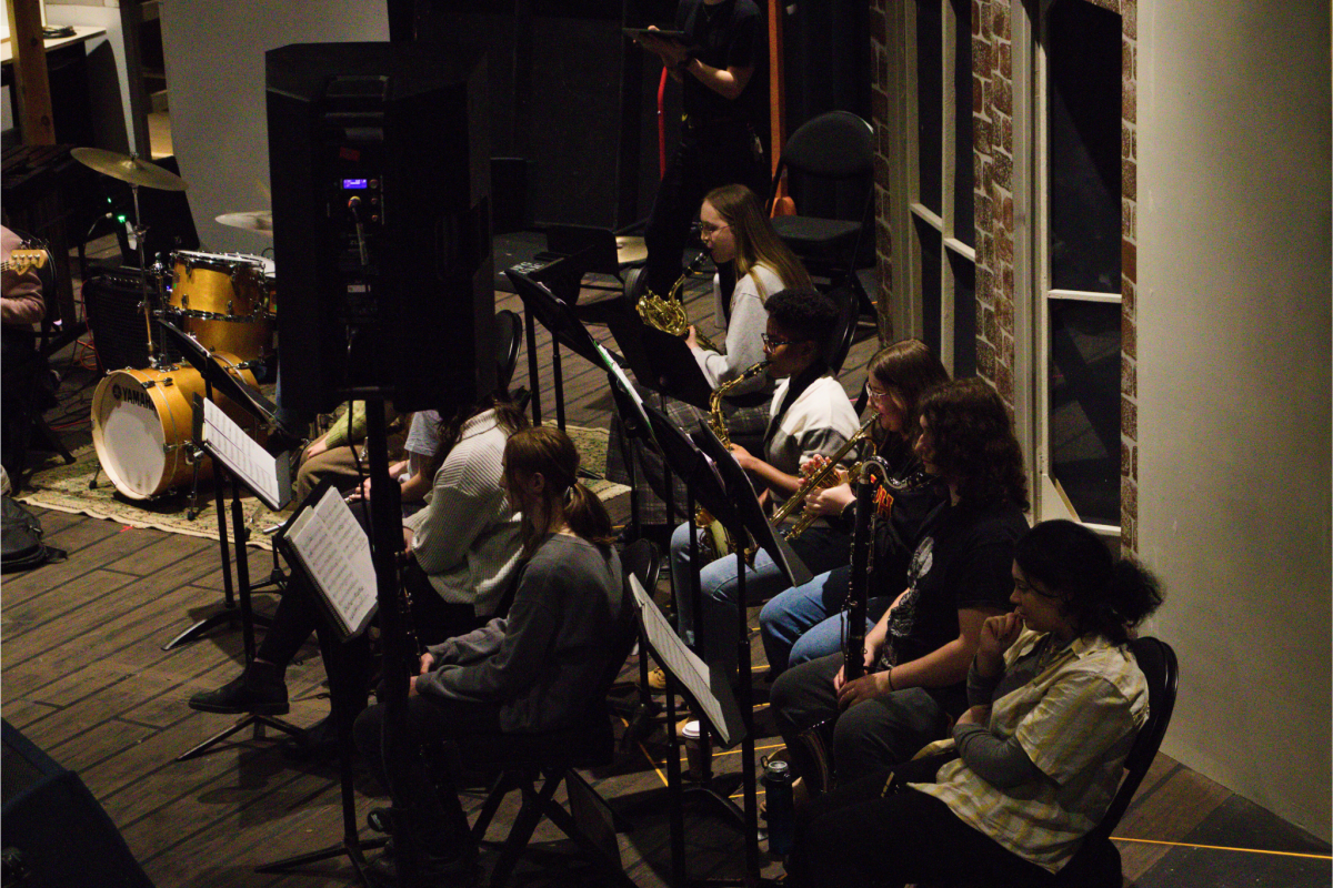 University of Guelph student ensemble members sitting in two rows rehearsing for the Little Shop of Horrors production.